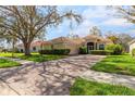 Single-story home with a paved driveway, landscaping, and large tree in front at 5195 Highbury Cir, Sarasota, FL 34238