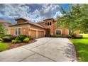 Two-story house with terracotta tile roof, landscaped yard, and a three-car garage at 20103 Shady Hill Ln, Tampa, FL 33647