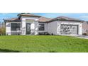 Inviting single-story home with lush green lawn, elegant entryway, and attached gray two-car garage at 5479 Brussels Ter, Port Charlotte, FL 33981
