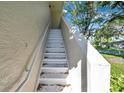 White metal stairs with handrail leading to condo unit, surrounded by stucco and landscaping at 2937 Bough Ave # D, Clearwater, FL 33760