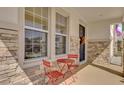 Inviting front porch with stone facade and red metal bistro set at 30684 Penny Surf Loop, Wesley Chapel, FL 33545