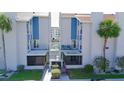 Charming condo featuring white exterior, blue accents, second floor balconies, and mature palms at 179 Medallion Blvd # C, Madeira Beach, FL 33708
