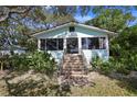 Charming light blue house with stone steps leading to the entrance, surrounded by lush greenery at 1820 1/2 N Washington Ave, Clearwater, FL 33755