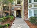 Exterior view of the condo complex showing stairs leading to units with stone facade and building number at 10108 Courtney Oaks Cir # 203, Tampa, FL 33619