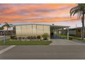Mobile home with covered carport, landscaped yard, and screened patio at sunset at 18675 Us Highway 19 N # 488, Clearwater, FL 33764
