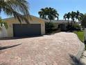 Charming home showcasing a brick driveway, mature palm trees, and a convenient two-car garage at 239 Punta Vista Dr, St Pete Beach, FL 33706