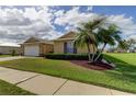 Tan house with palm trees and well-manicured lawn at 5220 Butterfly Shell Dr, Apollo Beach, FL 33572