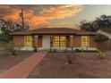 Charming single-story home featuring brick-paved driveway and a welcoming front entrance beneath a stunning sunset at 460 48Th S St, St Petersburg, FL 33711
