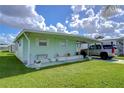 Light green mobile home with carport, landscaping, and a paved driveway at 5330 Vera St, Zephyrhills, FL 33542