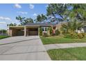 Tan house with carport, landscaping, and a red door at 3715 W Santiago St, Tampa, FL 33629