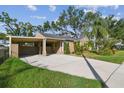 Tan house with carport, landscaping, and a red door at 3715 W Santiago St, Tampa, FL 33629