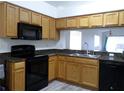 Kitchen features wood cabinets, granite countertops, and black appliances at 6820 Aramon Ct, Wesley Chapel, FL 33545