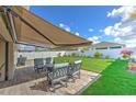 Outdoor patio with retractable awning, comfortable seating, and a manicured lawn at 555 Calico Scallop St, Ruskin, FL 33570