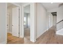 Hallway featuring hardwood floors, white walls, and a view into a bedroom and bathroom at 13804 Heartwood Way, Parrish, FL 34219