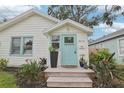 White bungalow with teal door, landscaping, and walkway at 2015 3Rd S St, St Petersburg, FL 33705