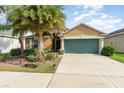 Tan house exterior with green garage door and palm trees at 12320 Ballentrae Forest Dr, Riverview, FL 33579