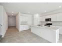 Bright kitchen with stainless steel appliances, white cabinets, an island, and tile flooring at 4187 Feldspar Ln, Spring Hill, FL 34609