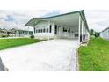 Front view of a white manufactured home with a carport at 37617 Amigo Dr, Zephyrhills, FL 33541