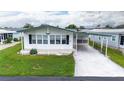 White manufactured home with green roof and landscaped yard at 37617 Amigo Dr, Zephyrhills, FL 33541