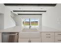 Bright, open-concept kitchen featuring a farmhouse sink, white cabinetry, and large windows overlooking the backyard at 35298 Big Hawk Dr, Zephyrhills, FL 33541