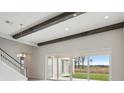 Spacious living room with high ceilings, wooden beams, and sliding glass doors leading to the outdoor space at 35298 Big Hawk Dr, Zephyrhills, FL 33541