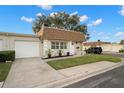 Tan house with white garage door, a manicured lawn, and mature trees at 8370 Burgundy N Dr # 8370, Pinellas Park, FL 33781