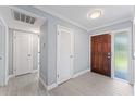 Open foyer with tile flooring, a wooden door, and neutral paint at 2132 Academy Dr, Clearwater, FL 33764