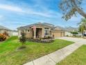 Two-story house with tan exterior, three-car garage, and landscaped yard at 2622 Bonterra Blvd, Valrico, FL 33594
