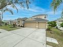 Two-story house with tan exterior, three-car garage, and manicured lawn at 2622 Bonterra Blvd, Valrico, FL 33594