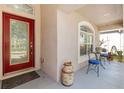 Front porch with red door, small table and chairs, and potted plants at 11449 Weston Course Loop, Riverview, FL 33579