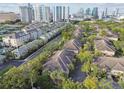 Aerial view showcasing a community of townhouses with lush greenery and a city skyline in the distance at 901 Normandy Trace Rd, Tampa, FL 33602