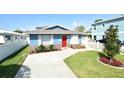 Inviting blue home boasts a red door, complemented by a lush green lawn and clear blue skies at 2918 10Th N St, St Petersburg, FL 33704