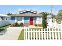Classic blue home featuring a red door and a charming white picket fence, surrounded by a well-kept lawn at 2918 10Th N St, St Petersburg, FL 33704