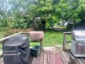 Deck with grill, spacious backyard, and lush green trees at 10006 N Mitchell Ave, Tampa, FL 33612
