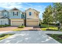 Two-story townhome with tan and teal exterior, two-car garage, and landscaping at 6330 Camino Dr, Apollo Beach, FL 33572