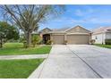 Tan house with lush landscaping, a three-car garage, and a spacious yard at 1433 Emerald Hill Way, Valrico, FL 33594