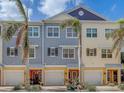 Three-unit townhouse building, featuring a blend of yellow and gray siding, and palm trees at 94 The Cove Way, Indian Rocks Beach, FL 33785
