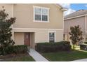 Tan two-story townhome with a brown door and landscaping at 27536 Desert Willow Way, Wesley Chapel, FL 33544