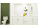 Double vanity bathroom with white cabinets and green accent wall at 10078 Gentle Rain Dr, Land O Lakes, FL 34638