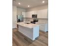 Modern kitchen with stainless steel appliances, island with sink, white cabinets and countertops at 2472 Mellow Ln, Clearwater, FL 33765