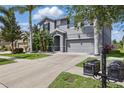 Gray two-story home with an attached two-car garage, complemented by tropical landscaping at 12013 Whistling Wind Dr, Riverview, FL 33579