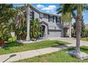 Charming gray two-story home with tropical landscaping and a well-manicured lawn at 12013 Whistling Wind Dr, Riverview, FL 33579