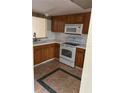 Galley kitchen with wood cabinets and white appliances at 6345 Newtown Cir # 45A3, Tampa, FL 33615