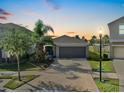 Charming single-Gathering home featuring a two-car garage and lush landscaping during sunset at 16912 Yellow Pine St, Wimauma, FL 33598