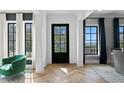 Elegant foyer featuring hardwood floors, stylish black front door, and windows offering serene outdoor views at 5811 Mariner St, Tampa, FL 33609