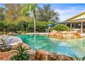 Gorgeous swimming pool featuring rock accents, stone pavers, and lush tropical landscaping at 2501 Rustic Oaks Dr, Lutz, FL 33559