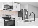 Modern kitchen featuring stainless steel appliances, white cabinetry, light countertops and a stylish backsplash at 615 W Virginia Ave, Tampa, FL 33603