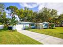 Light blue house with a large yard and driveway at 1042 Idlewild N Dr, Dunedin, FL 34698