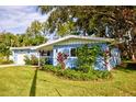 Updated light blue home with a lush, manicured lawn at 1042 Idlewild N Dr, Dunedin, FL 34698