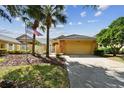 Exterior of a house with a tan garage, stone accents, and palm trees at 13141 Palmilla Cir, Dade City, FL 33525